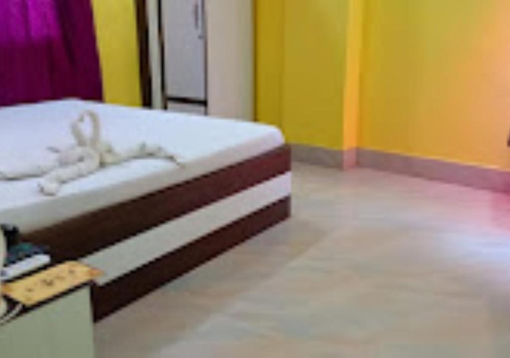 uma cama num quarto com paredes amarelas e verdes em Hotel Gitanjali Malda em Māldah