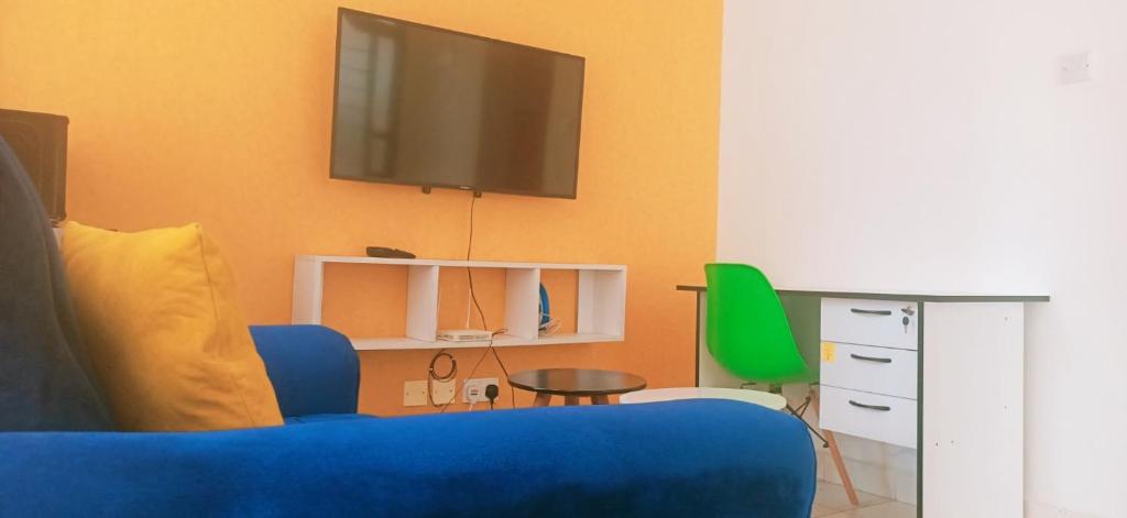 ein Wohnzimmer mit einem blauen Sofa und einem TV in der Unterkunft Racecourse Gardens Apartment in Nairobi