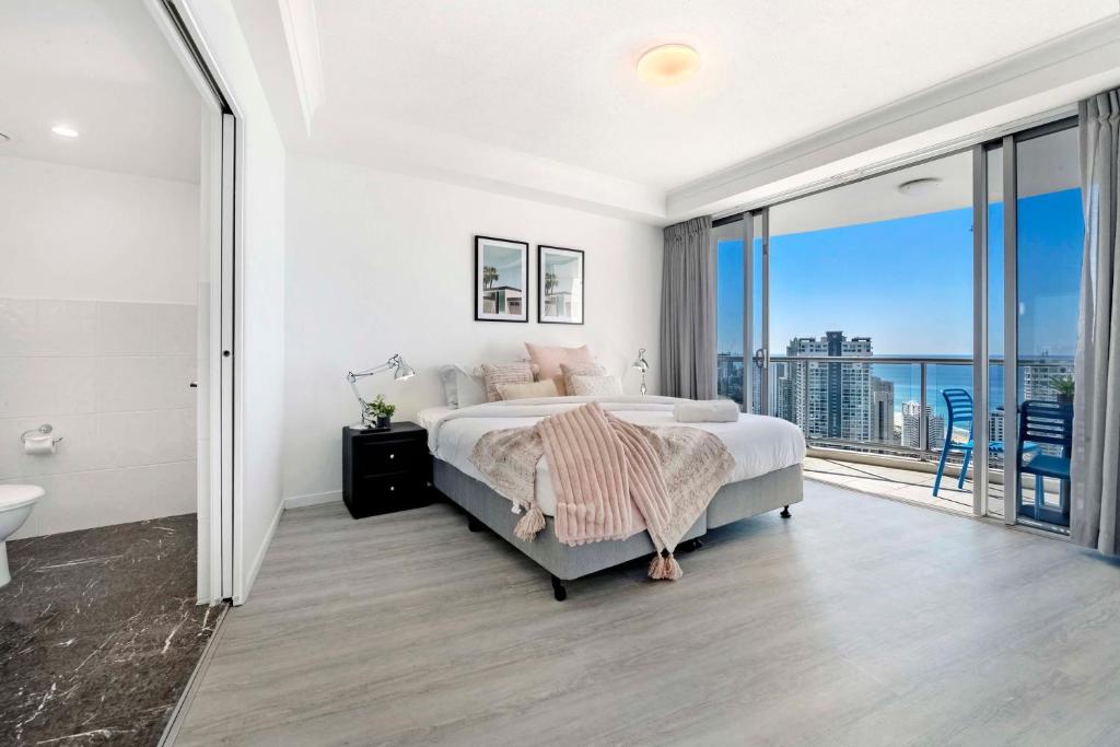 a white bedroom with a bed and a balcony at 3 Bedroom Apartment with Ocean Views in Central Location - Chevron Renaissance - Wow Stay in Gold Coast