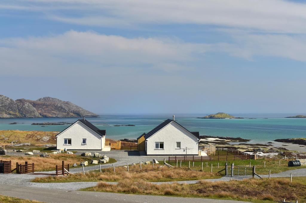 two white cottages on a hill next to the ocean at Rockpool in Pollachar