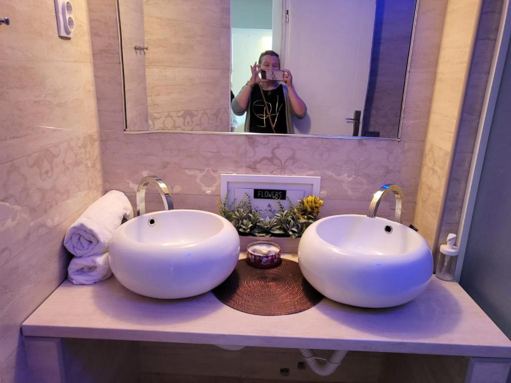 una mujer tomando una foto de dos lavabos en un baño en Vila Marija, en Ribarska Banja