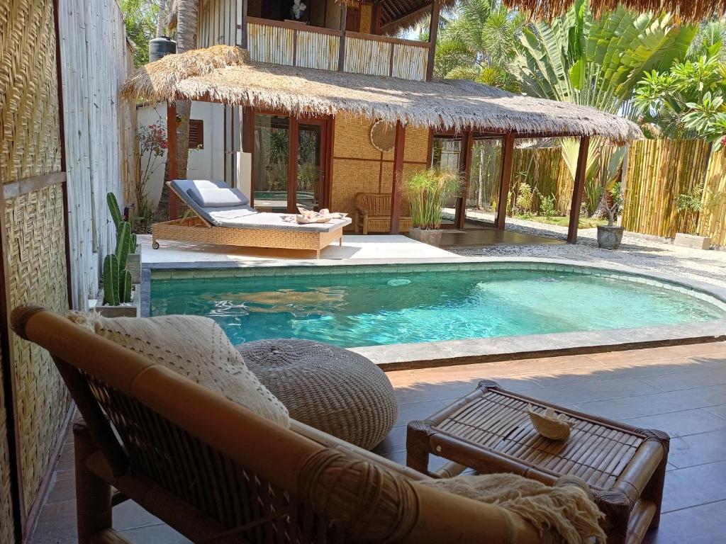 a swimming pool with a couch and a chair next to it at Villa Maiya in Gili Islands