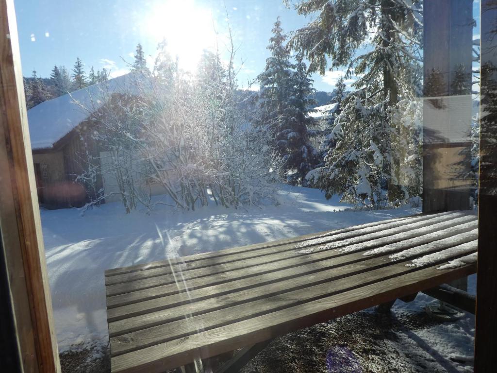 a snow covered yard with a bench in a window at Chalet Beaujon Chapelle-des-Bois in Chapelle-des-Bois