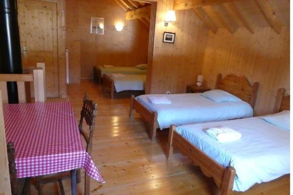 a room with three beds in a wooden room at Chalet Beaujon Chapelle-des-Bois in Chapelle-des-Bois