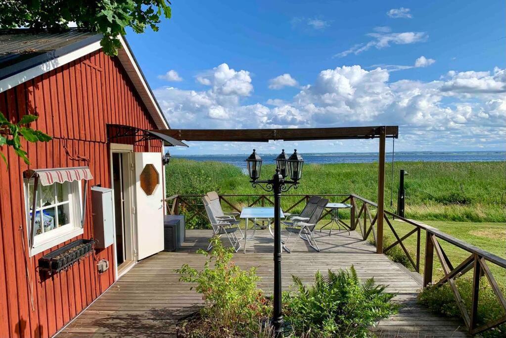 eine Holzterrasse mit einem Tisch und Stühlen auf einem Haus in der Unterkunft Flemma Gård By the lake in Vreta Kloster