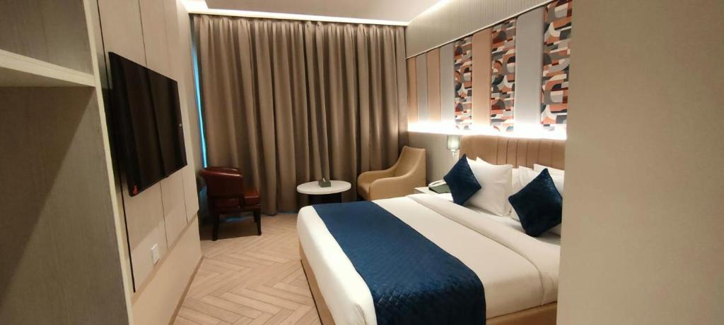 um quarto de hotel com uma cama e uma cadeira em Chinmay Hotel & Resort em Lucknow