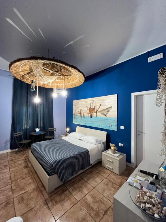 una camera da letto con pareti blu, un letto e un lampadario a braccio di Marini Bed&Breakfast a Pescara