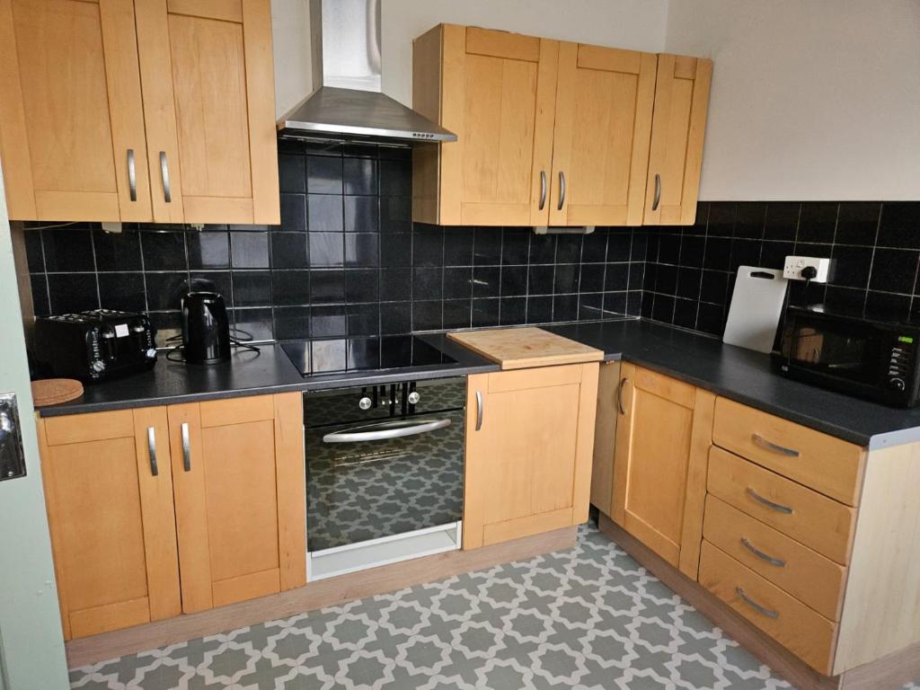 una cocina con armarios de madera y encimeras negras en Rectory5 - 5 bedroom 7 beds Parking Perfect for Contractors, en Gateshead
