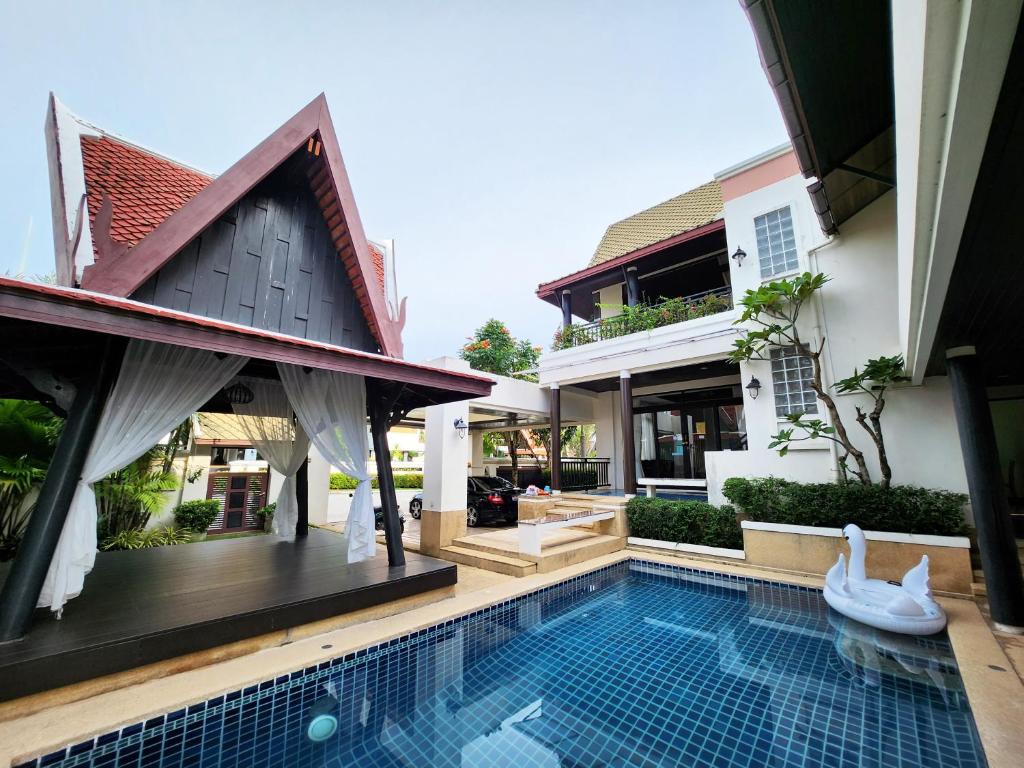 une maison avec une piscine en face d'une maison dans l'établissement รมิดา พูล วิลล่า พัทยา Ramida Pool Villa Pattaya, à Jomtien Beach