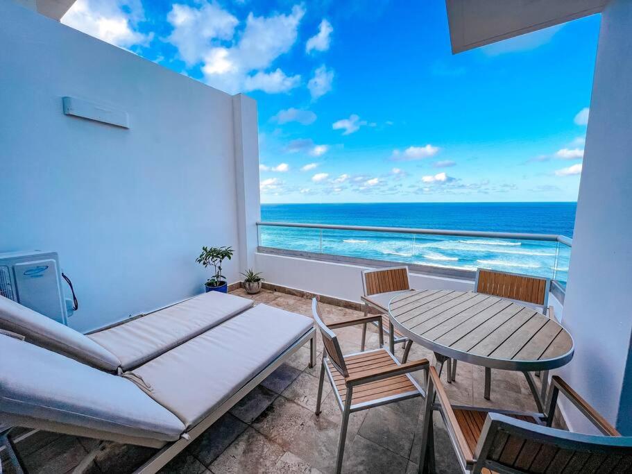 uma varanda com mesa e cadeiras e vista para o oceano em Luxurious SubPh Apt Atlantis W/ Ocean View & PRK em San Juan