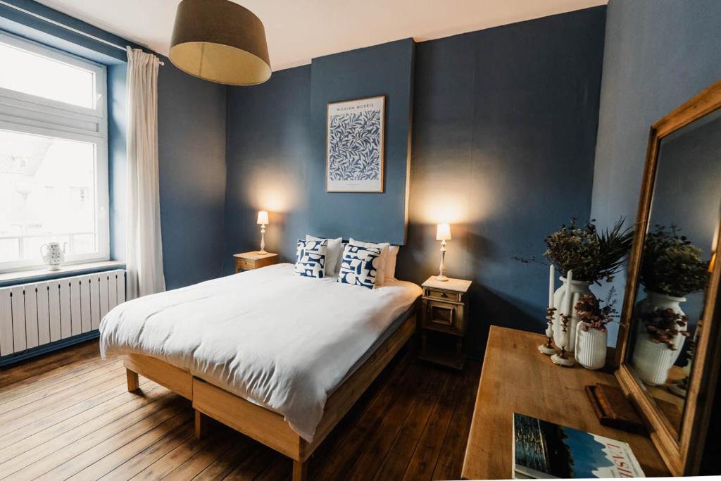 een slaapkamer met een bed met blauwe muren en een spiegel bij Maison Comtale in Rochefort