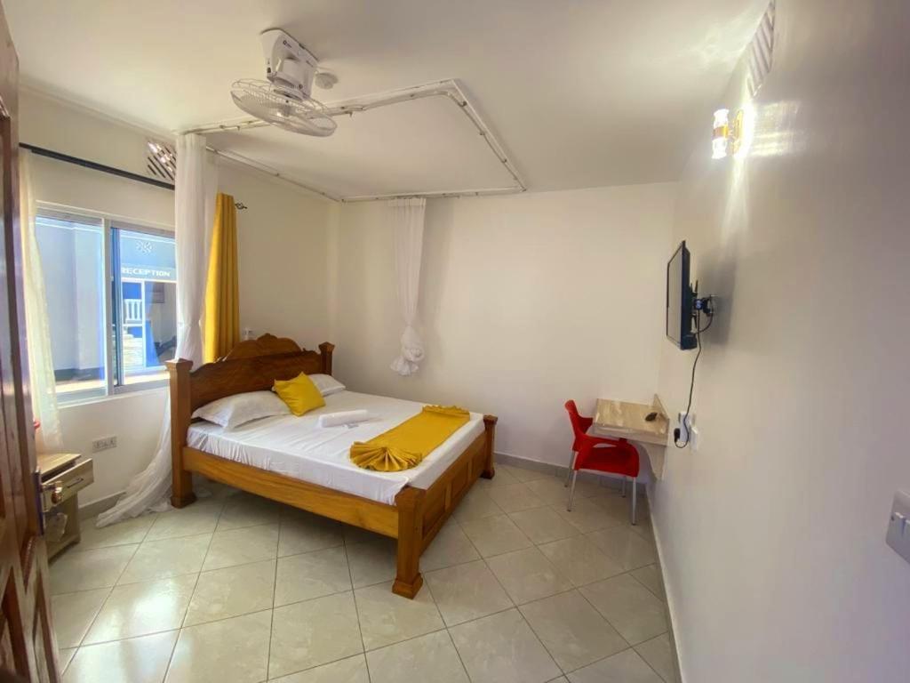 - une chambre avec un lit doté d'oreillers jaunes dans l'établissement Mtwapa Texas Villa Guest House, à Mtwapa