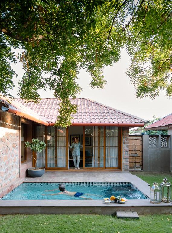 a woman standing in the doorway of a house with a swimming pool at Surpura Bagh - A Luxury Boutique Resort in Jodhpur