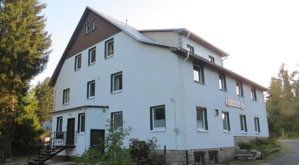 ein weißes Gebäude mit braunem Dach in der Unterkunft Pension Waldhaus in Eibenstock