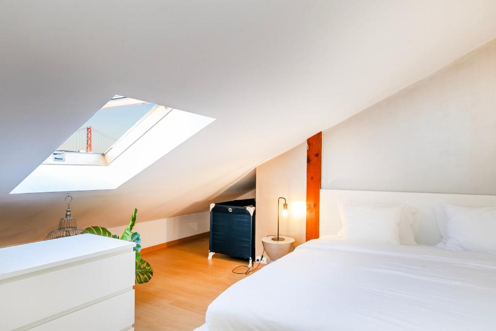 een slaapkamer met een wit bed en een dakraam bij Belém Sweet Spot in Lissabon