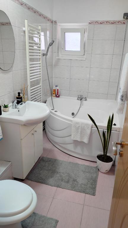 e bagno bianco con vasca, servizi igienici e lavandino. di Noua Apartment a Braşov