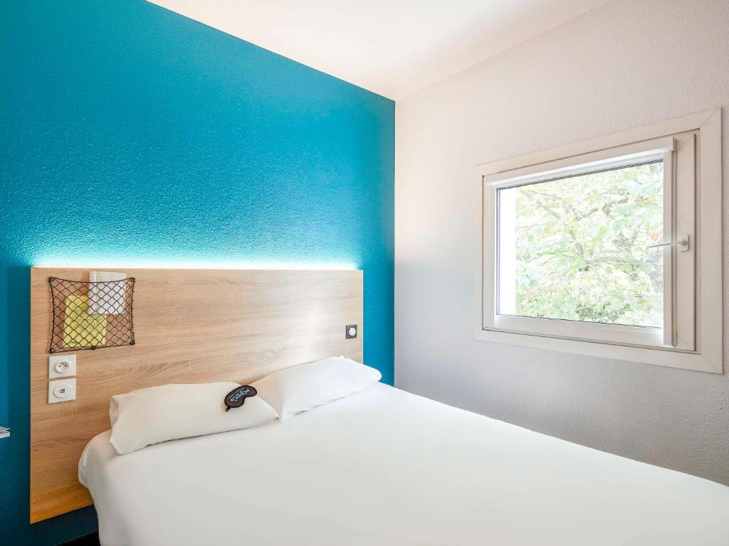 1 dormitorio con cama blanca y ventana en hotelF1 Merlebach Saarbrueck, en Merlebach