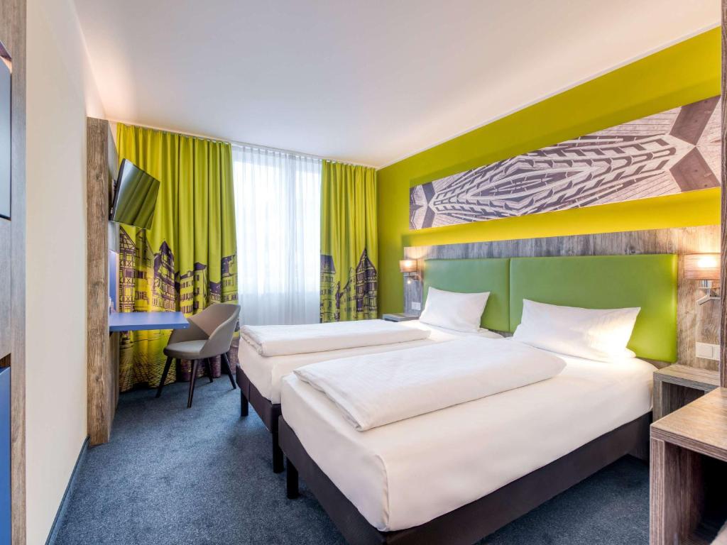 a hotel room with two beds and a desk at ibis Styles Tuebingen in Tübingen
