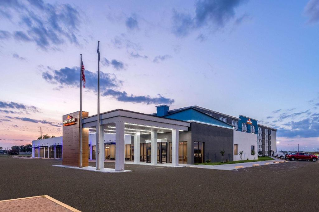 a large building with a flag in a parking lot at Hawthorn Extended Stay by Wyndham Wichita Airport in Wichita