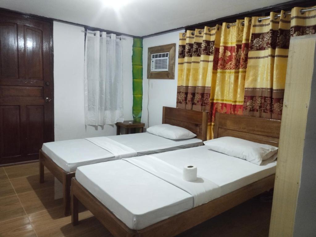 two beds in a room with colorful curtains at Ziah's Guest House in San Vicente