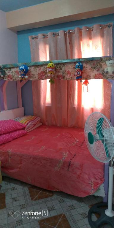 - une chambre avec un lit rouge et un ventilateur dans l'établissement Blue Haven Unit 1, à Baguio