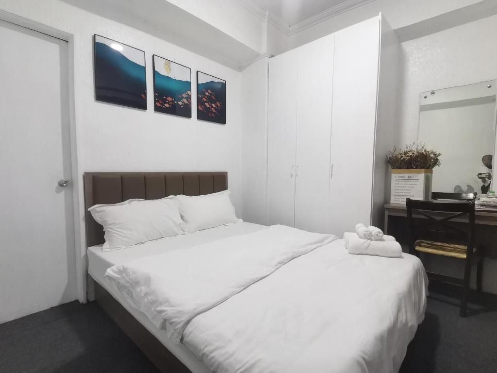 um quarto com uma grande cama branca e uma secretária em Accommodation services-anne em Manila