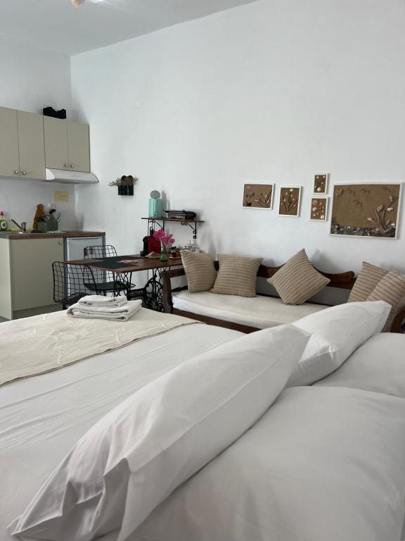 2 camas con sábanas blancas en una habitación en Estia κατάλυμα στο Μύρτος, en Myrtos
