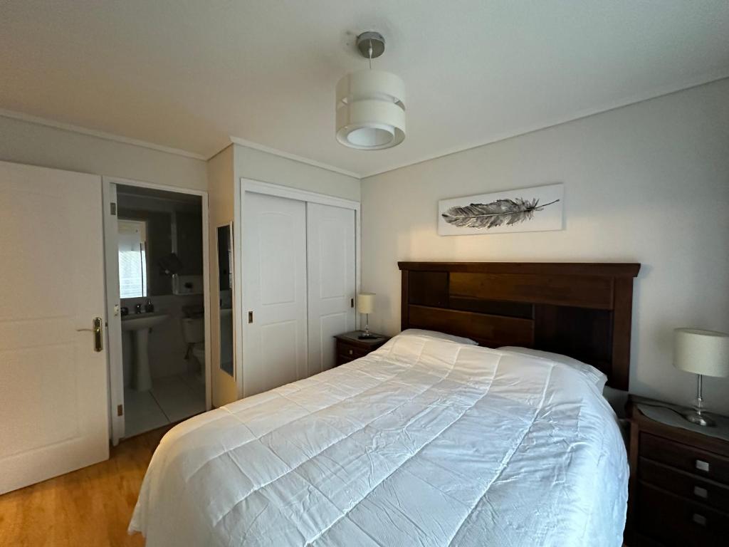 1 dormitorio con 1 cama blanca grande y baño en Depto Las Condes - San Pascual, en Santiago