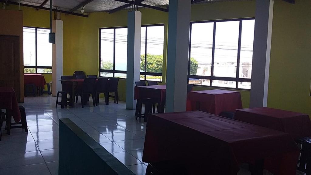 uma sala de jantar com mesas, cadeiras e janelas em La esquina del capitán em San Vicente