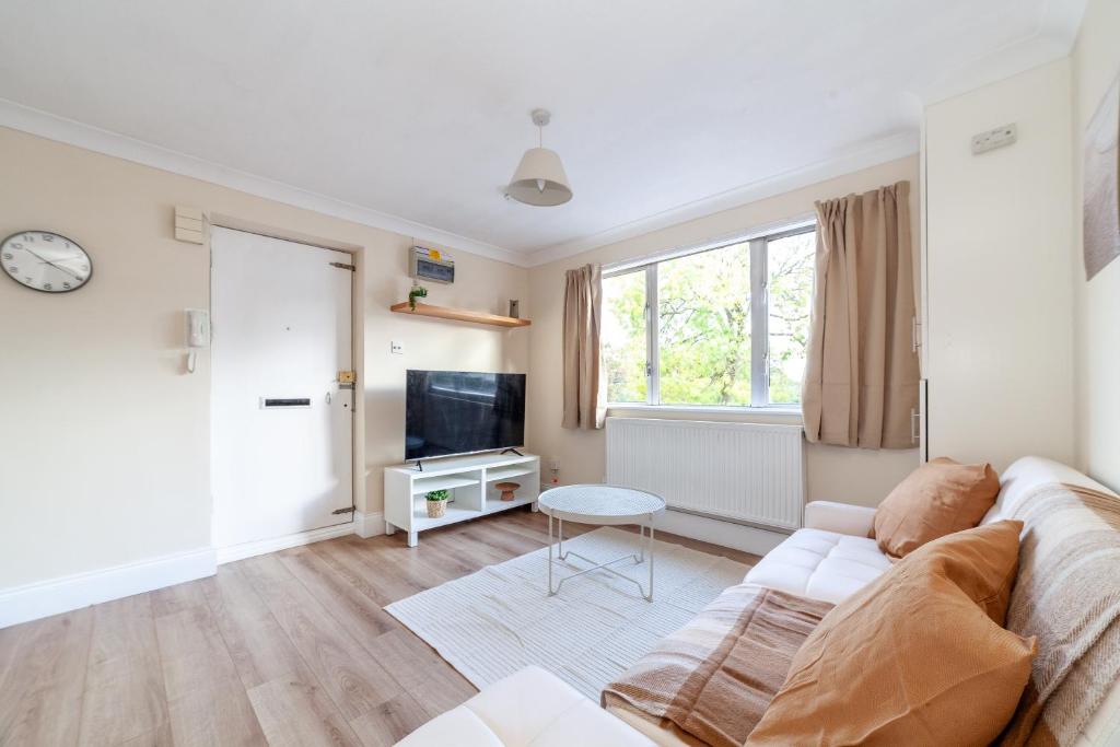 Hotel Lovely Studio Flat in Wimbledon w/ Free Parking, a living room with a couch and a tv at Lovely Studio Flat in Wimbledon w/ Free Parking in London