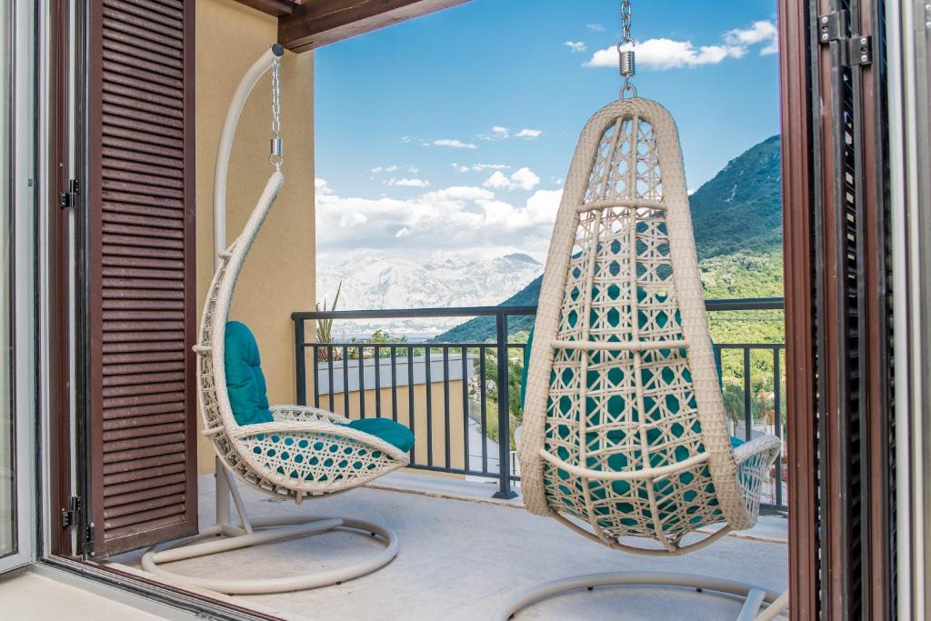a balcony with two chairs and a swing at Lavender Bay Apartment in Donji Morinj