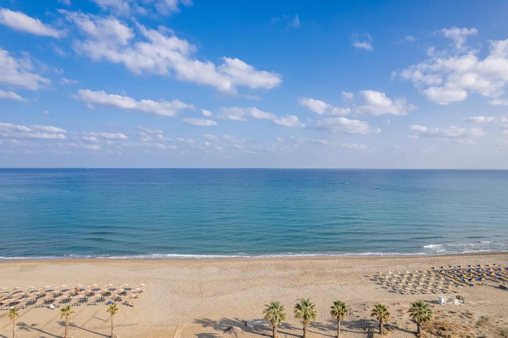 an empty beach with palm trees and the ocean at Domenica Apartments in Rethymno