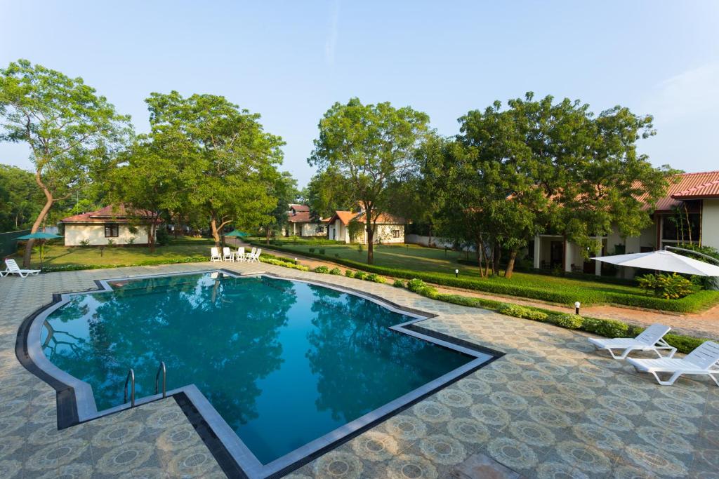 a swimming pool with chairs and a house in the background at Hotel Chenra in Kataragama