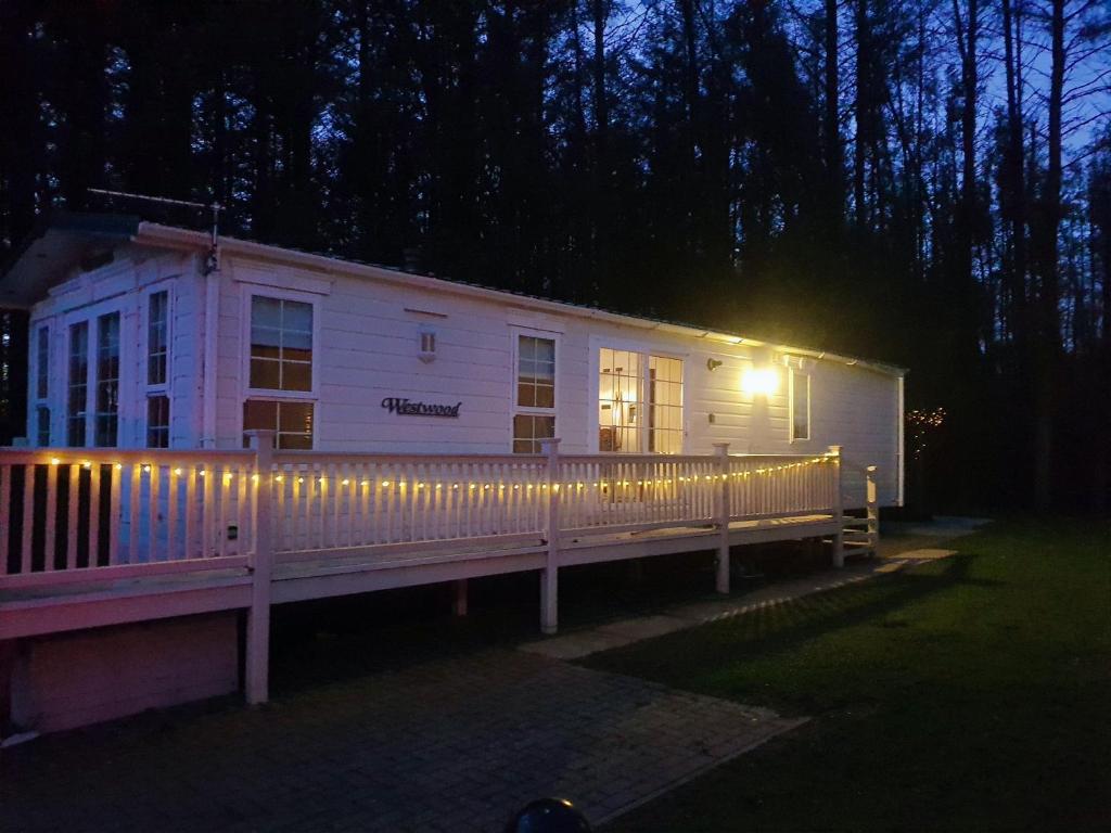 a house with lights on the side of it at night at Woodland Hot Tub Retreat in Swarland