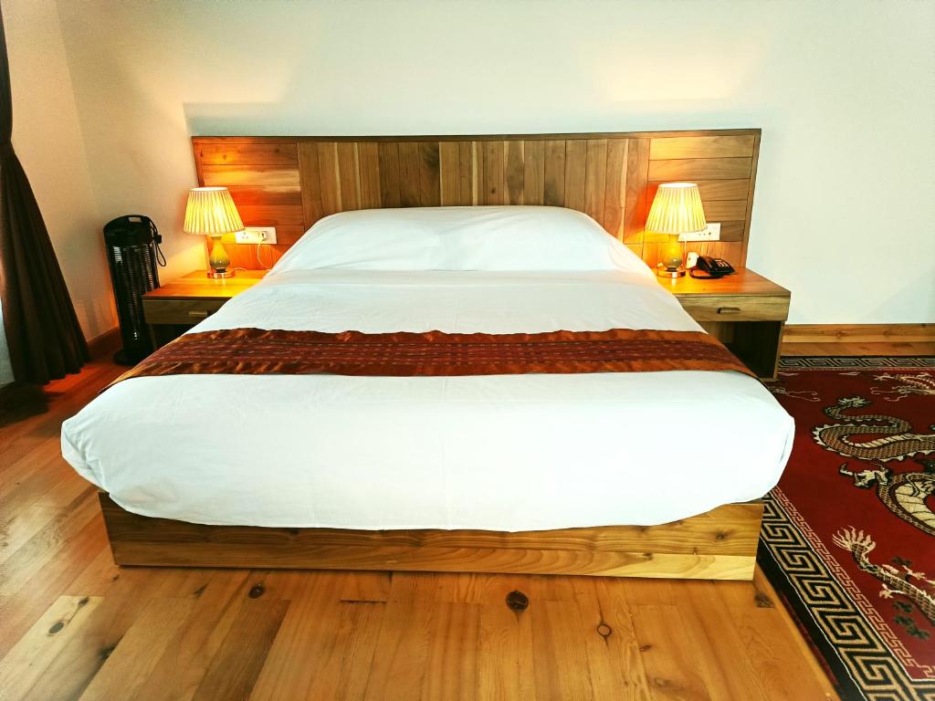 duże łóżko w sypialni z dwoma lampami na dwóch stołach w obiekcie Jagathang Village Inn w mieście Paro