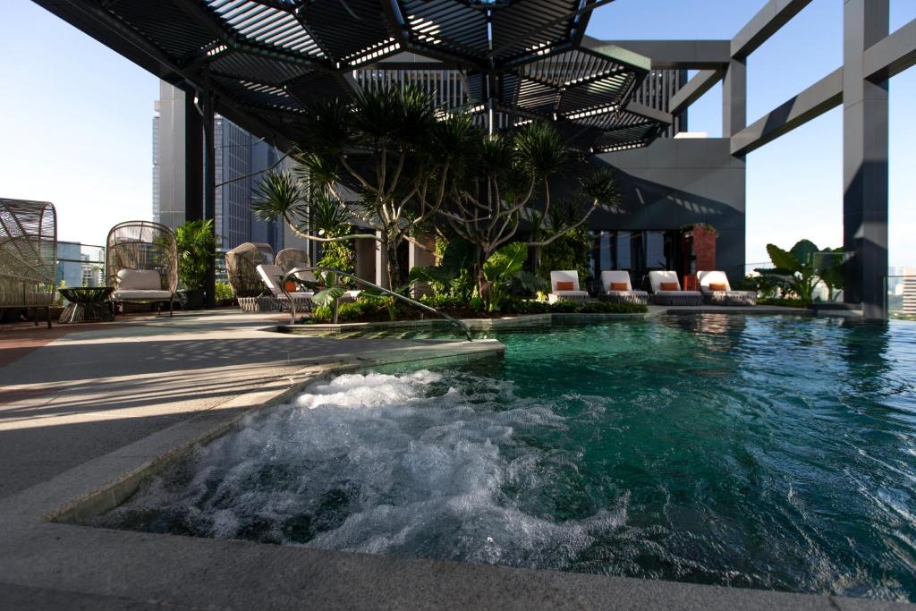 A rooftop pool includes a bubbling spa section beneath a slatted pergola.