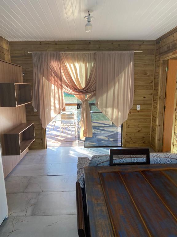 um quarto com uma cama e uma janela com cortinas em Recanto Nativos em Garopaba