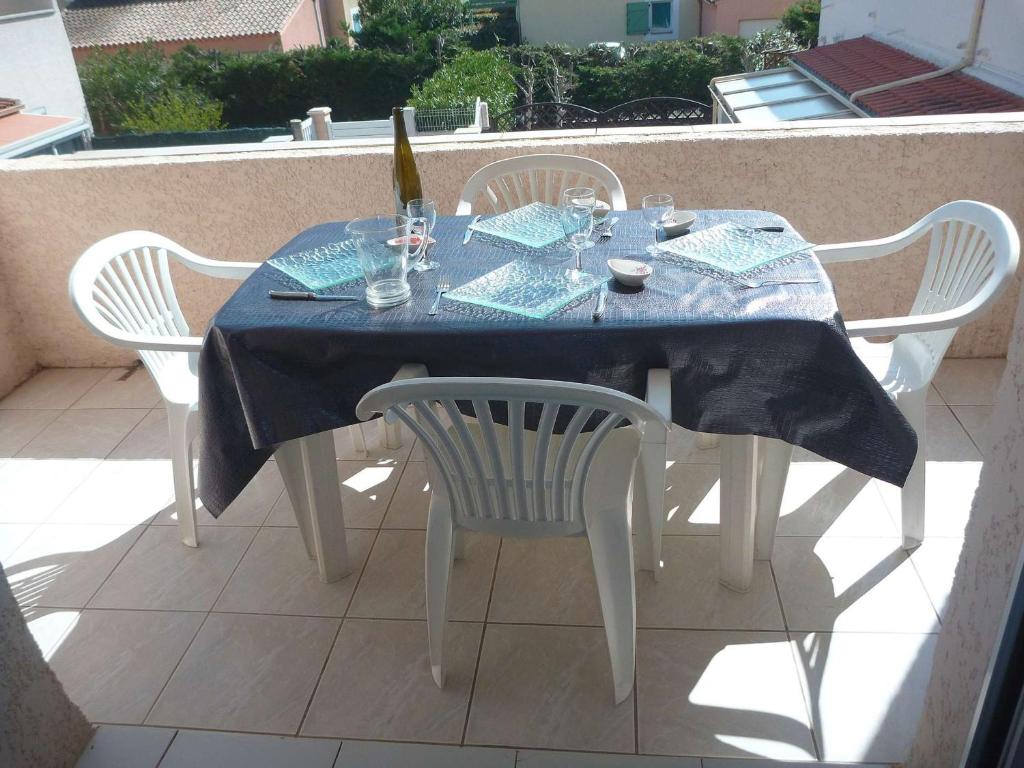 - une table avec 2 chaises et une bouteille de vin dans l'établissement Appartement lumineux avec clim, terrasse et parking à Marseillan - FR-1-387-35, à Marseillan