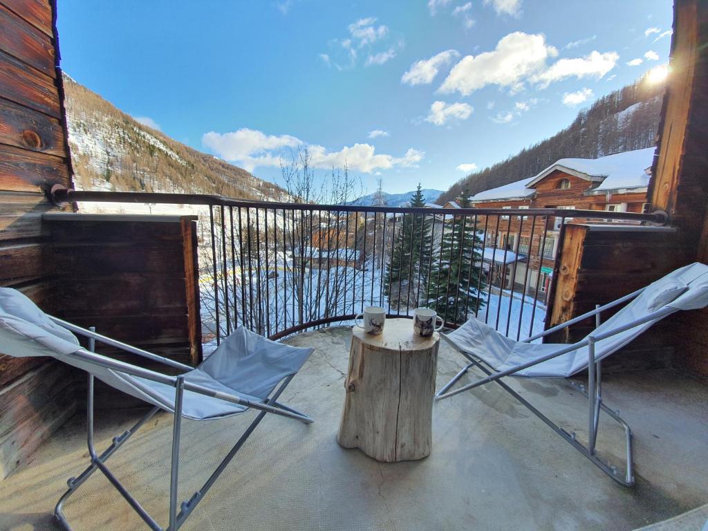 two chairs and a stump on a porch with a tree stump at La Foux d'Allos -Le Centre - Appartement T2 cosy et lumineux en cœur de station in La Foux