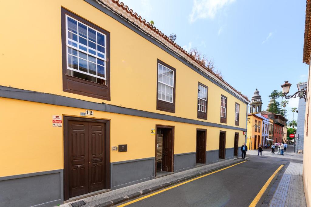 a yellow building with brown doors on a street at Marhaba La Laguna, alojamiento en centro histórico de San Cristóbal de La Laguna in Las Lagunas