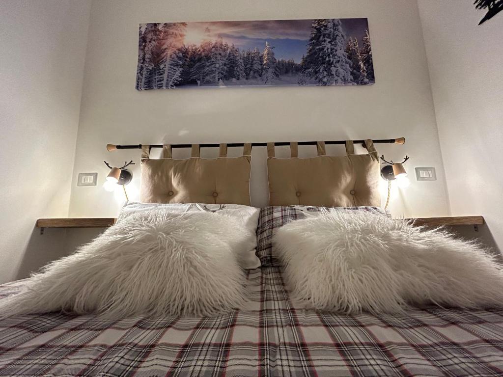 une chambre avec un lit avec deux oreillers blancs dessus dans l'établissement Casa Genziana - nuovo bilocale in centro a Sestriere, à Sestrières