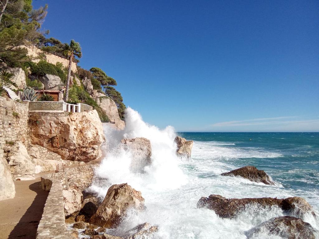 a beach with waves crashing on the rocks at Voilier tout confort in Beaulieu-sur-Mer