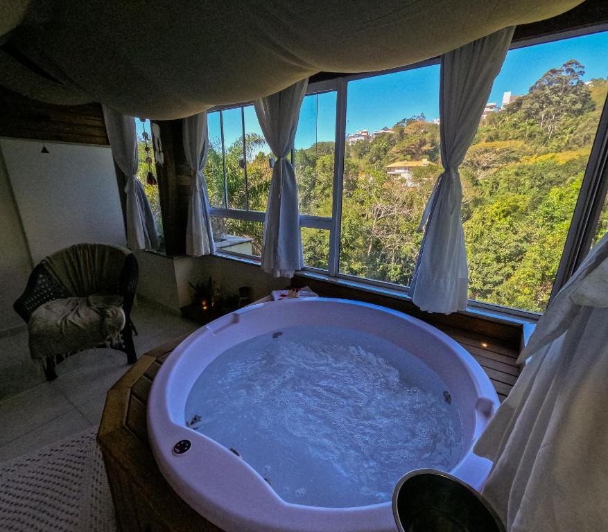 a bath tub in a room with a view at Bombinhas Guest House in Bombinhas