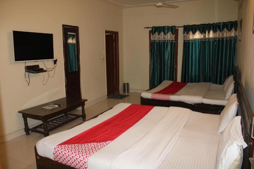 two beds in a room with a tv and a table at HOTEL NEW APPLE ROSE in Chandīgarh