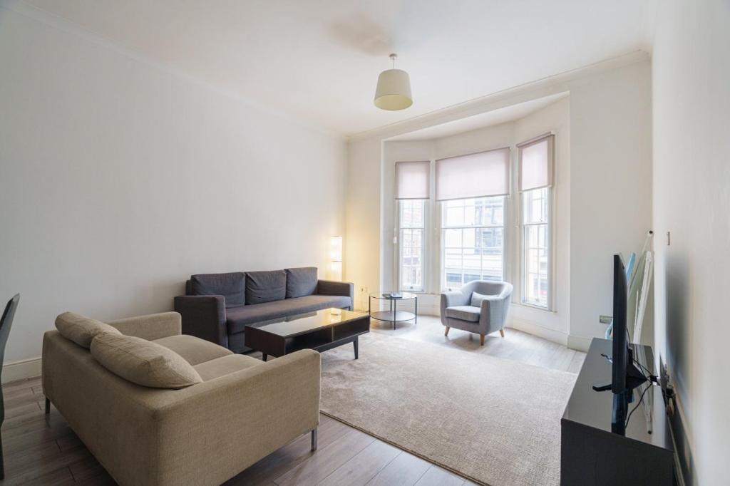 a living room with a couch and a tv at The Apartments Kensington High Street in London
