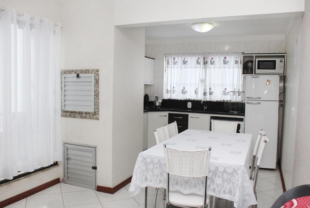 Il comprend une cuisine équipée d'une table blanche et d'un réfrigérateur blanc. dans l'établissement Cantinho Aconchegante Morada do Sol, à Piratuba