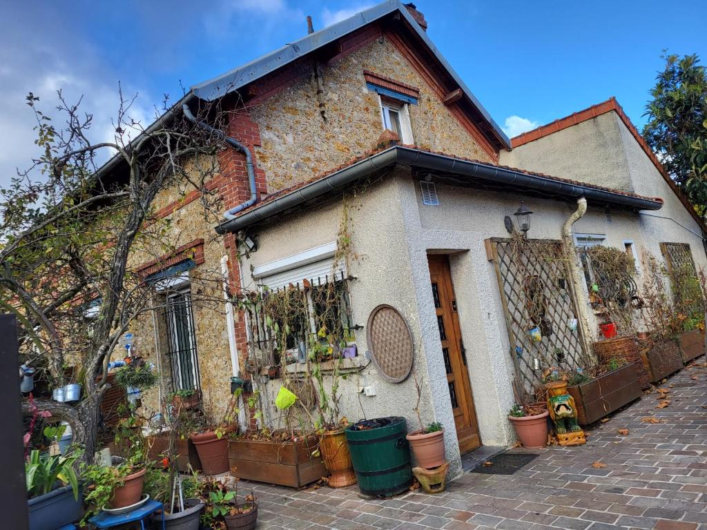 una casa de ladrillo con macetas delante de ella en Maison JO 2024 en Guyancourt