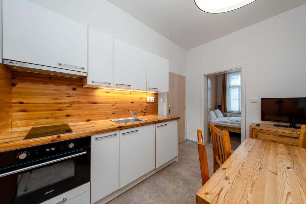 a kitchen with white cabinets and a wooden table at Pension Janský Potok I. in Janske Lazne
