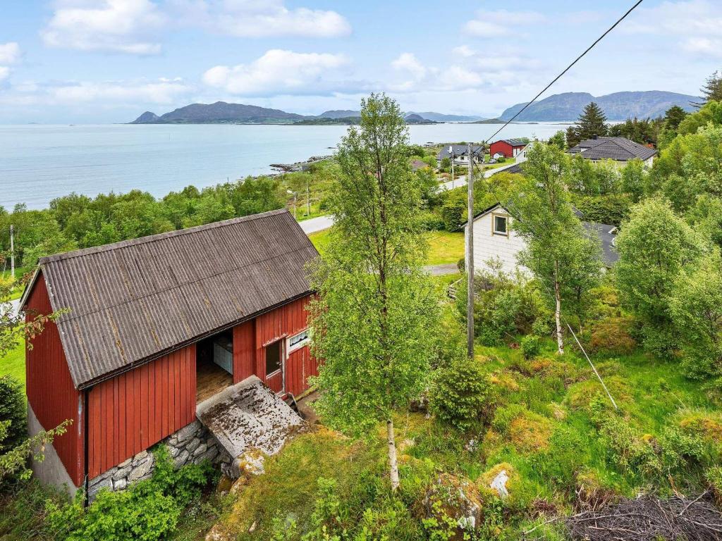 a red house on a hill next to a body of water at Holiday home Åram in Sandvik