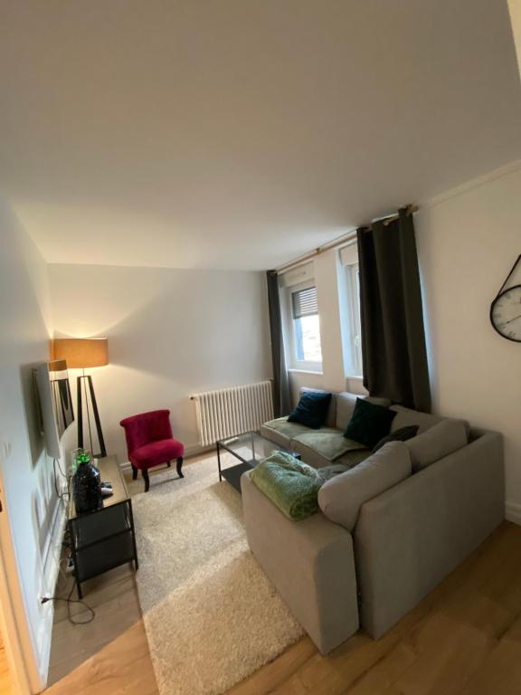 sala de estar con sofá y silla roja en Appartement Marceau Courbevoie, en Courbevoie